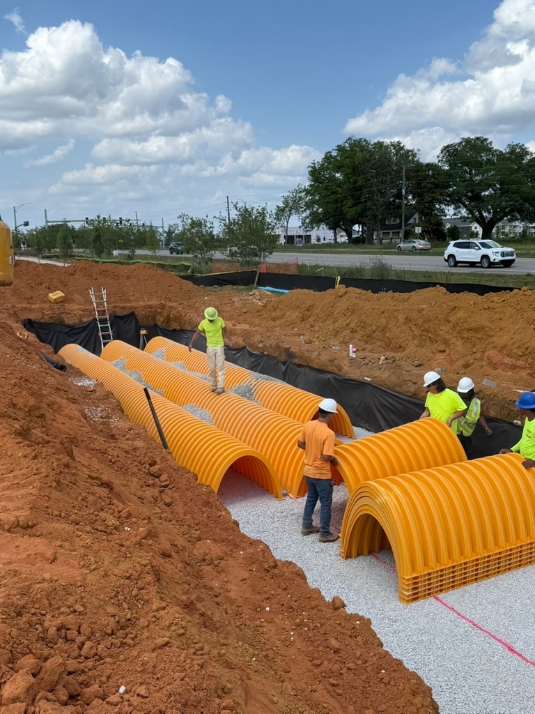 Crew installing an underground stormwater chamber system in an open excavation